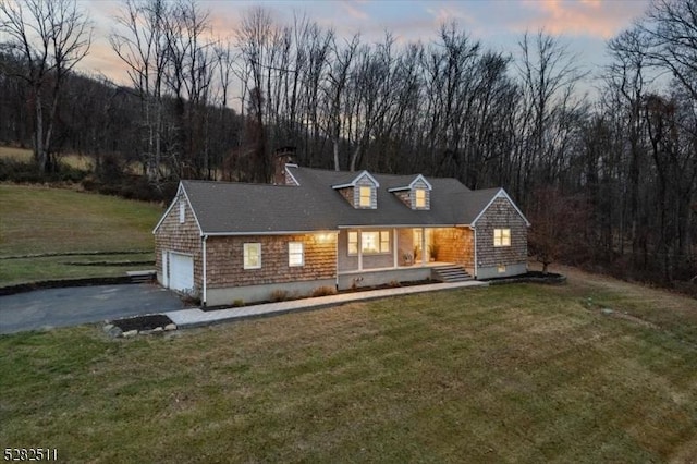 cape cod house with a garage, a porch, and a yard