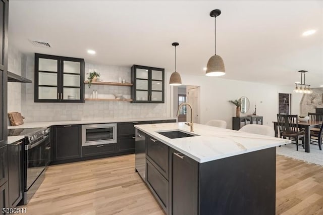 kitchen featuring sink, light hardwood / wood-style flooring, hanging light fixtures, an island with sink, and stainless steel appliances