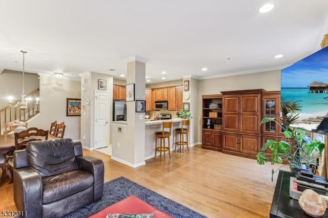 living room featuring an inviting chandelier, light hardwood / wood-style floors, and crown molding