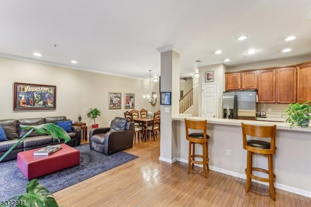 kitchen featuring kitchen peninsula, stainless steel fridge with ice dispenser, a kitchen bar, light wood-type flooring, and crown molding