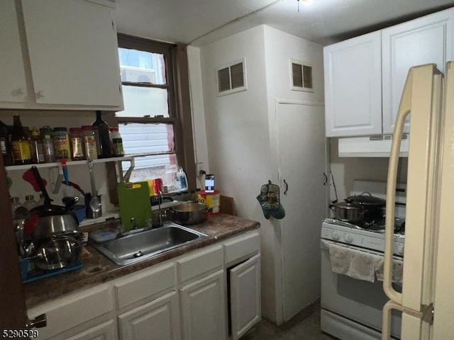 kitchen with white cabinets, fridge, white range with gas stovetop, and sink