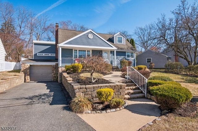 view of front of property featuring a porch, driveway, a garage, and roof with shingles