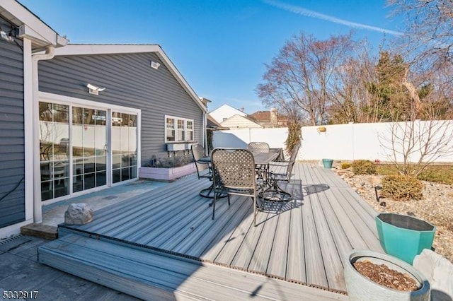 wooden terrace with outdoor dining space and a fenced backyard