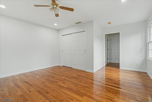 unfurnished bedroom featuring light hardwood / wood-style flooring, ceiling fan, and a closet