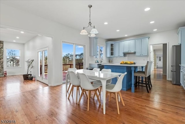 dining space featuring light wood-type flooring, plenty of natural light, and a notable chandelier