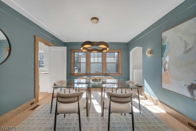 dining space featuring ornamental molding, a notable chandelier, and light hardwood / wood-style flooring