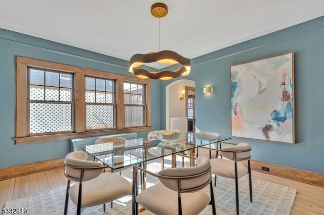 dining space with wood-type flooring and ornamental molding