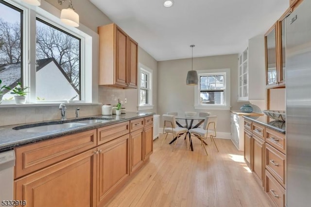 kitchen with sink, backsplash, hanging light fixtures, white dishwasher, and light wood-type flooring