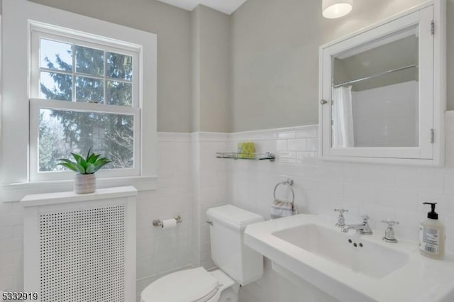 bathroom with tile walls, sink, toilet, and a shower with shower curtain