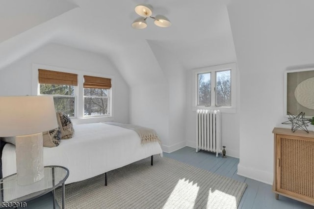 bedroom featuring lofted ceiling, radiator, hardwood / wood-style floors, and multiple windows