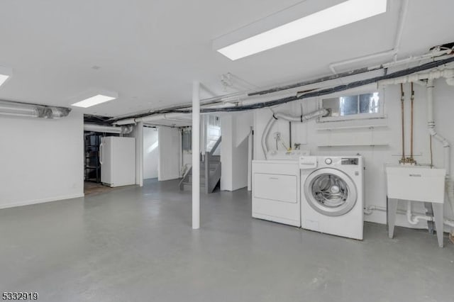 basement featuring washing machine and dryer and white fridge