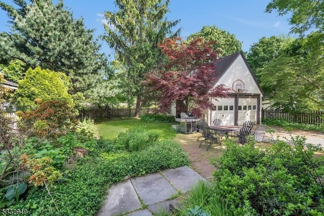 view of yard with a garage, a patio, and an outbuilding