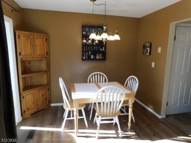 dining space with visible vents, baseboards, a notable chandelier, and wood finished floors