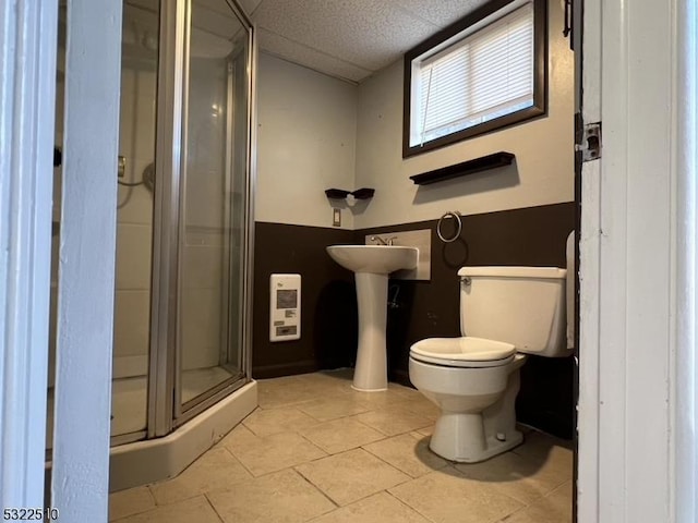 bathroom featuring toilet, a drop ceiling, tile patterned floors, sink, and a shower with shower door