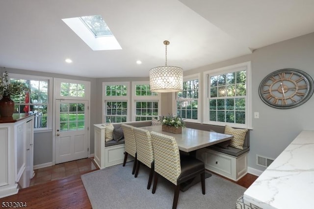 dining room with dark wood-type flooring, vaulted ceiling with skylight, plenty of natural light, and breakfast area