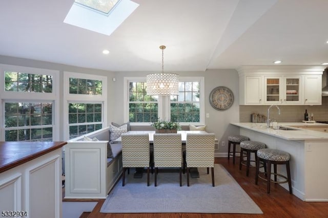 dining space featuring a skylight, dark hardwood / wood-style flooring, and sink