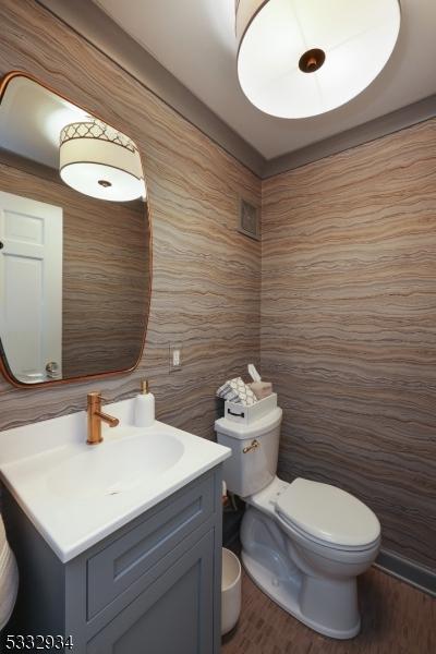 bathroom with toilet, vanity, and wood-type flooring