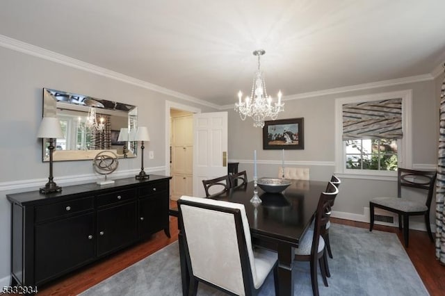 dining area featuring dark wood-type flooring, crown molding, and a notable chandelier