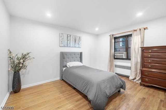 bedroom with light wood-type flooring, cooling unit, and radiator