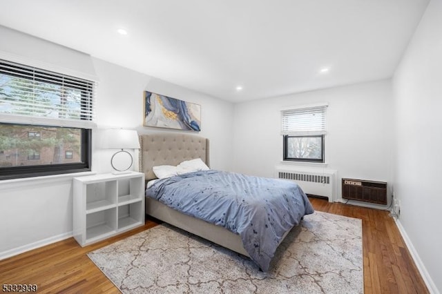 bedroom with radiator, an AC wall unit, and hardwood / wood-style floors