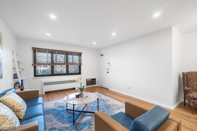 living room with a wall unit AC, hardwood / wood-style flooring, and radiator