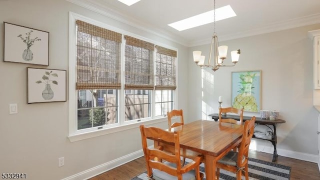 dining area with a skylight, dark wood-type flooring, a chandelier, and ornamental molding