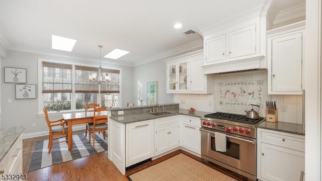 kitchen featuring kitchen peninsula, a skylight, designer range, and white cabinetry