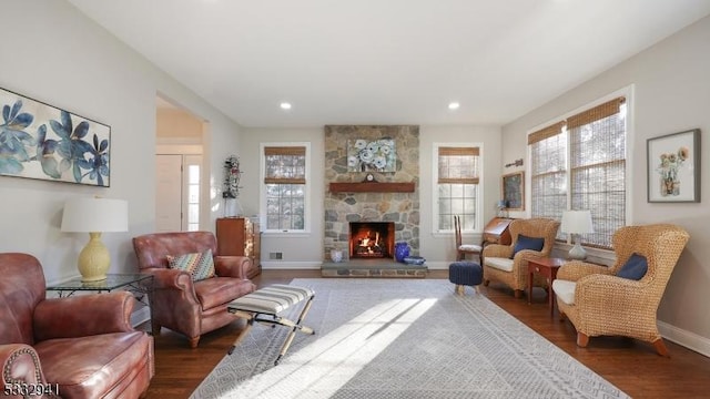 living room with dark hardwood / wood-style floors and a stone fireplace