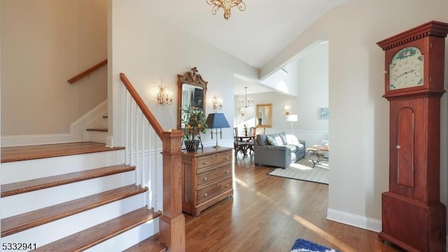 foyer entrance featuring high vaulted ceiling, dark wood-type flooring, and a notable chandelier