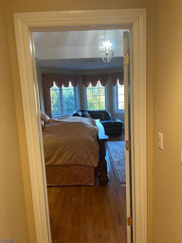 bedroom with hardwood / wood-style floors and an inviting chandelier