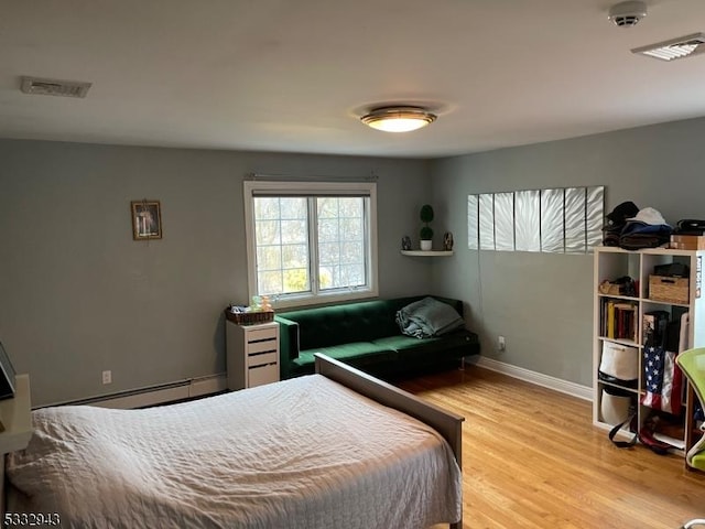 bedroom featuring a baseboard heating unit and light wood-type flooring