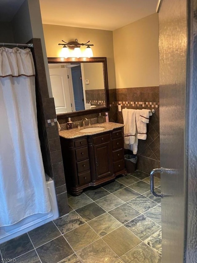 bathroom with vanity, tile walls, and shower / bath combination with curtain