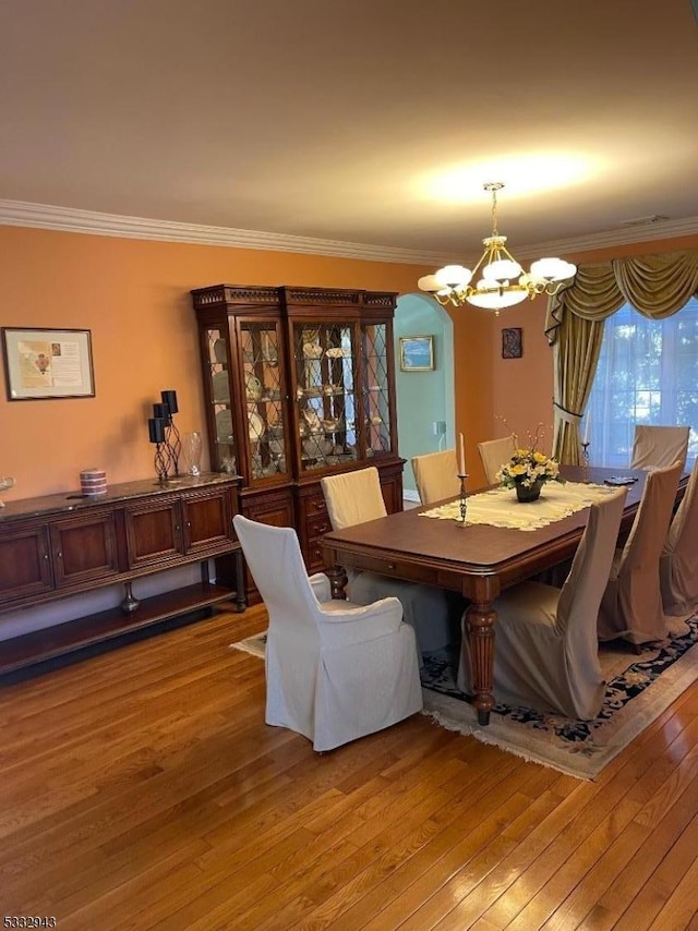 dining area featuring hardwood / wood-style floors, crown molding, and a chandelier