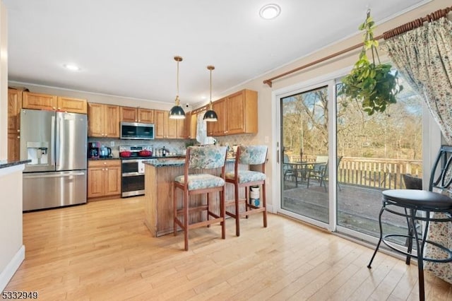 kitchen featuring a kitchen bar, appliances with stainless steel finishes, tasteful backsplash, hanging light fixtures, and crown molding