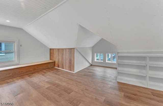 additional living space featuring lofted ceiling, wood-type flooring, and built in shelves