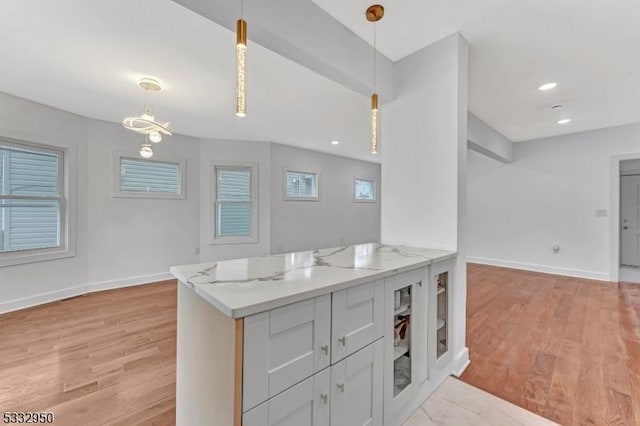 kitchen featuring light stone counters, light hardwood / wood-style flooring, pendant lighting, and white cabinetry