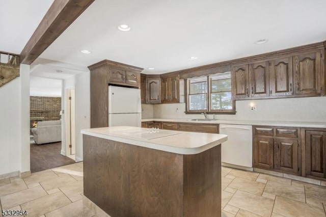 kitchen with white appliances, a kitchen island, beamed ceiling, a fireplace, and sink