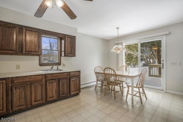 dining room with sink, a baseboard radiator, and ceiling fan with notable chandelier