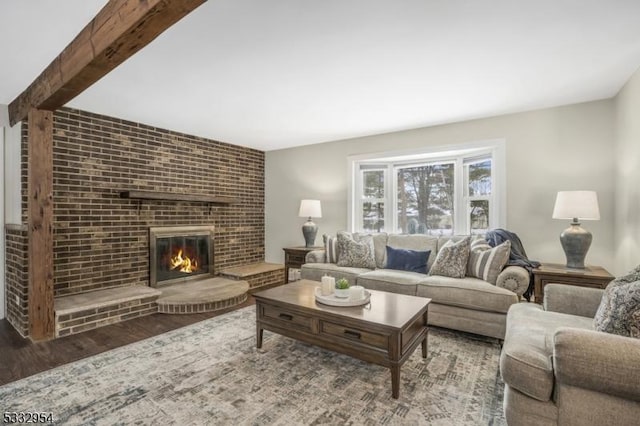 living room featuring a brick fireplace, wood-type flooring, and beamed ceiling