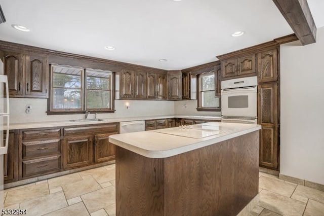 kitchen with beamed ceiling, white appliances, a center island, sink, and dark brown cabinets