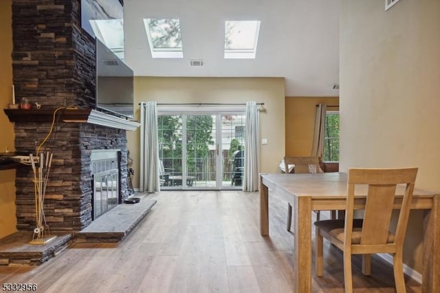 interior space with a skylight, a stone fireplace, and hardwood / wood-style flooring