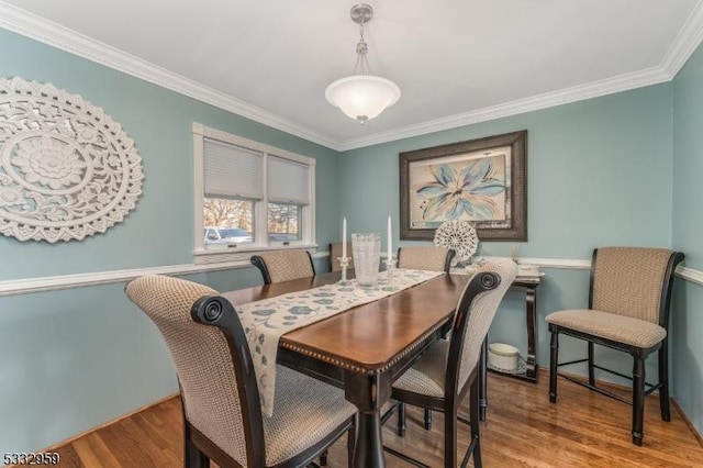 dining area featuring light wood-type flooring and crown molding