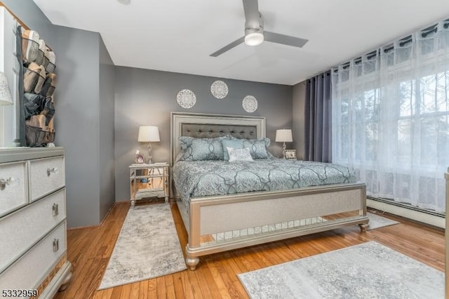 bedroom featuring ceiling fan, a baseboard radiator, and light hardwood / wood-style floors