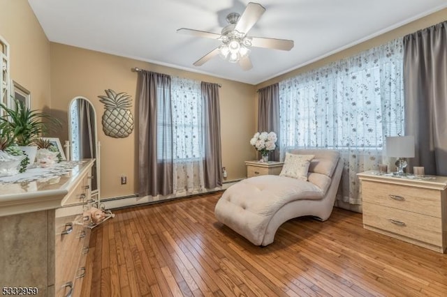 sitting room featuring a baseboard heating unit, ceiling fan, and light hardwood / wood-style floors