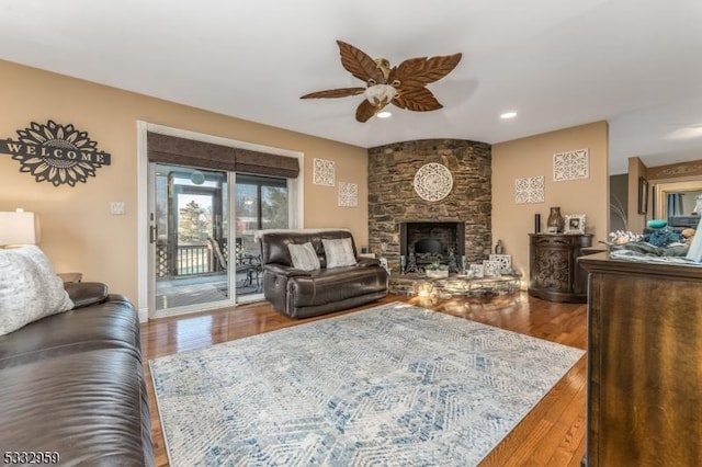 living room featuring ceiling fan, a fireplace, and wood-type flooring