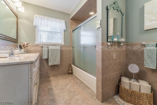 bathroom featuring bath / shower combo with glass door, tile walls, tile patterned floors, and vanity