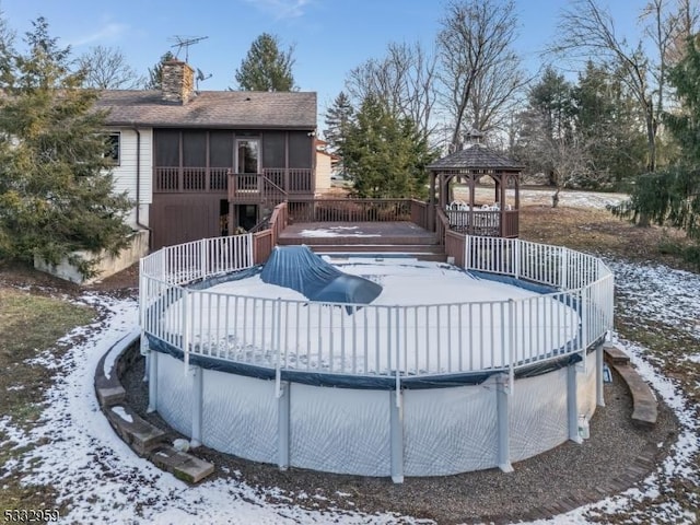 snow covered pool featuring a gazebo, a wooden deck, and a sunroom