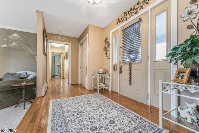 foyer entrance with baseboard heating and light hardwood / wood-style floors