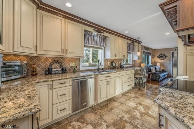 kitchen featuring light stone countertops, dishwasher, cream cabinetry, and decorative light fixtures