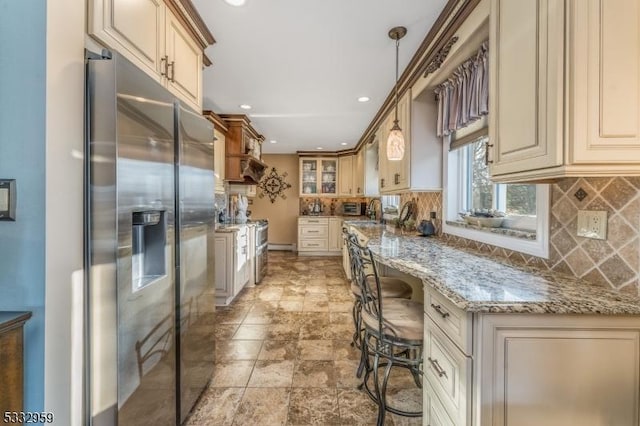 kitchen featuring backsplash, pendant lighting, a kitchen breakfast bar, stainless steel fridge with ice dispenser, and light stone counters